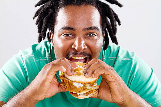 istock overweight african american man eating hamburger 154347012