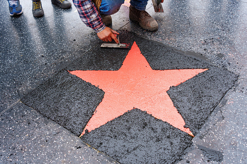 Los Angeles, California - January 3, 2023: Worker finishing the installation of a star on the Hollywood Walk of Fame, top-down view.