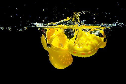 Kyiv, Ukraine - June 6, 2023: Yellow Crocs Submerged in Water with Splashes