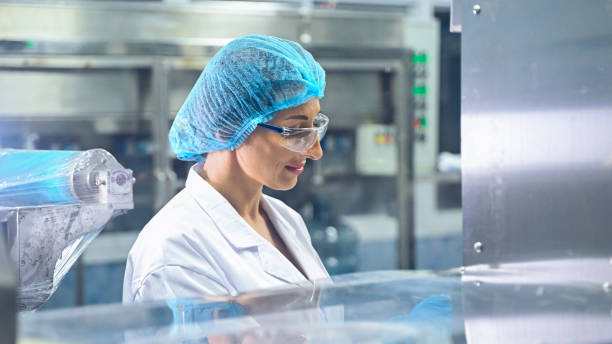 Bottling factory worker inspecting quality of water bottles before shipment. Reverse osmosis system used in plant. water purity and maintaining quality control in bottling process. High quality photo. trabajador de la fábrica embotelladora inspeccionando la calidad de las botellas de agua antes del envío. sistema de ósmosis inversa utilizado en planta. pureza del agua y mantenimiento del control de calidad en el proceso de embotellado. foto de alta c