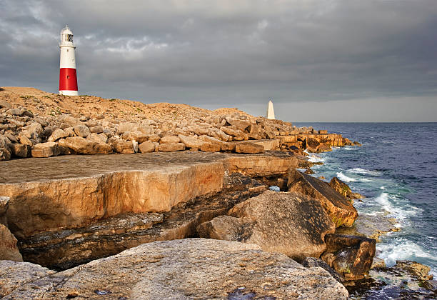 istock Victorian lighthouse on promontory of rocky cliffs 154354425