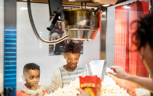 Two kids buying fresh popcorn from concession stand in a movie theater