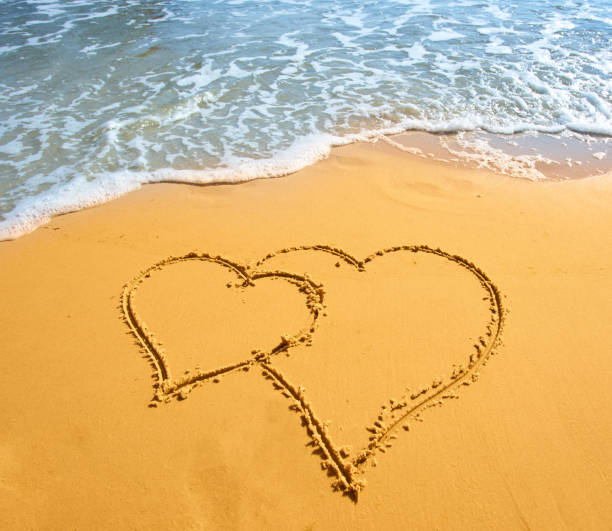 istock Two hearts handwritten on sand of tropical beach 1543602275