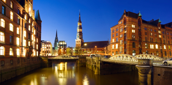 Warehouse district ( Speicherstadt ) of Hamburg at night with view towards the city center including the St. Catherine's Church and St. Nikolai.