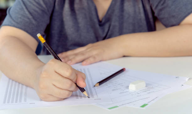 istock Students hand holding pencil writing selected choice on answer sheets and Mathematics question sheets. students testing doing examination. school exam 1543648206