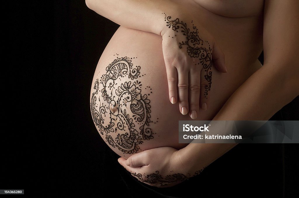 Henna Tattoo on a Woman's Pregnant Belly and Hands A photo of henna tattoo paste on a woman's hands and pregnant belly. Henna application in the 8th month of pregnancy is an ancient practice believed to bring an easy birth and healthy child. Henna Tattoo Stock Photo