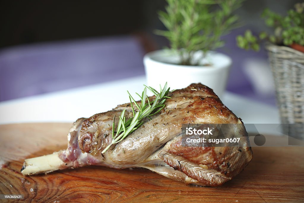 Roasted leg of lamb with rosemary on the cutting board Roasted leg of lamb with rosemary on the cutting board in the domestic kitchen. Lamb - Meat Stock Photo