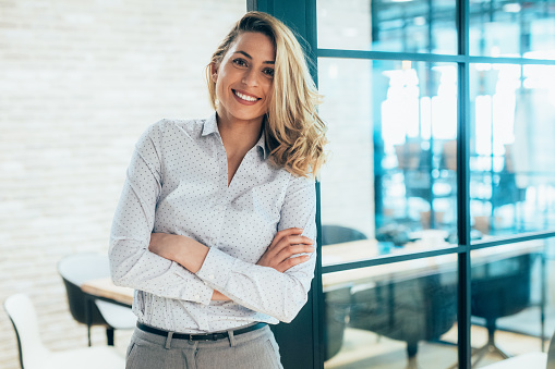 Portrait of Beautiful business woman smiling at the modern office. Female business entrepreneur looking at camera with arms crossed