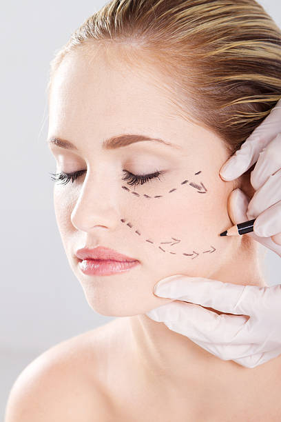 istock doctor draw correction lines on woman face 154368536