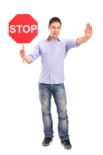 Full length portrait of a man gesturing and holding a traffic sign stop isolated against white background