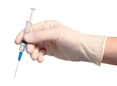 Syringe in gloved hand, isolated on white background