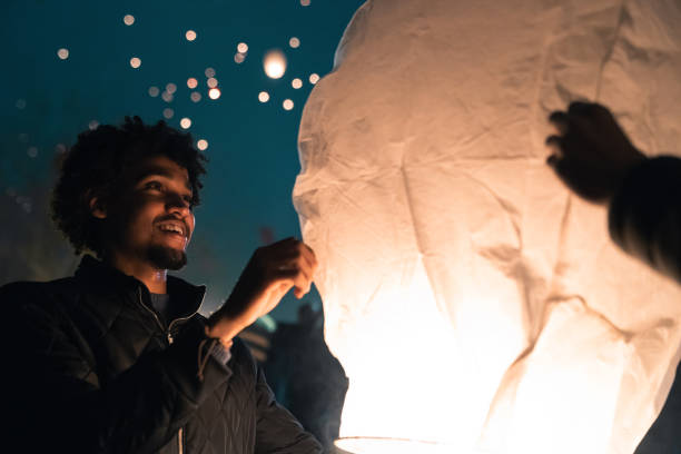 istock Joyful handsome young man lighting up a paper sky lantern at Asian event at night 1543719826