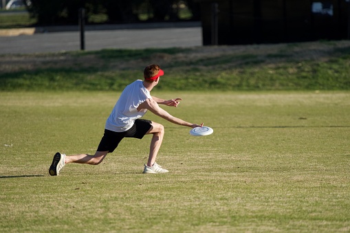College Park, MD, USA-March 23: Man wearing red hats playing frisbee on the lawn under sun
