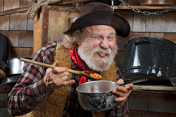 istock Hungry old cowboy eating beans from a saucepan 154380610