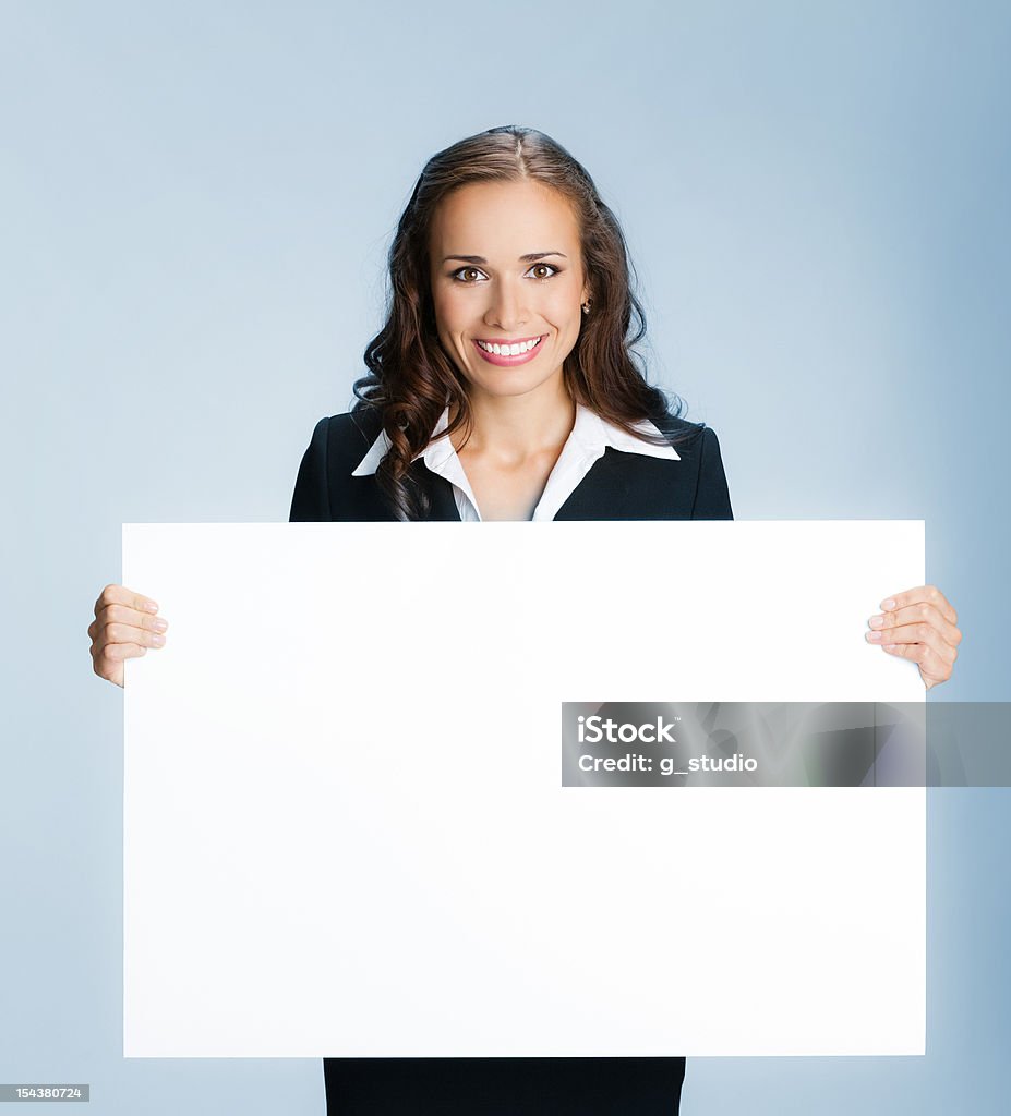 Smiling businesswoman holding a blank sign board Happy smiling young business woman showing blank signboard, over blue background 20-29 Years Stock Photo