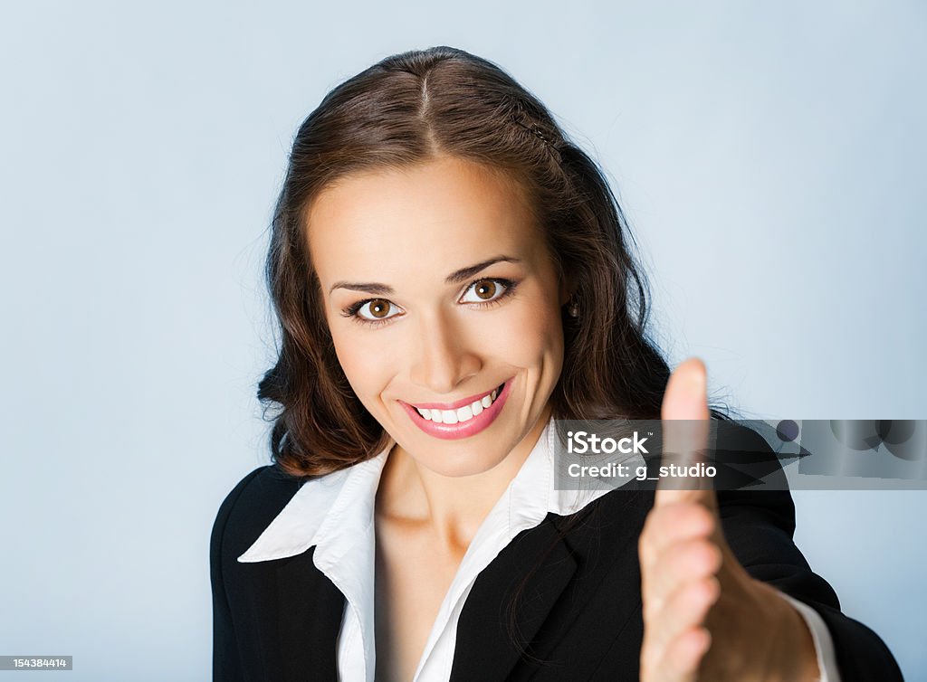 Business woman giving hand for handshake, over blue Portrait of young cheerful beautiful business woman giving hand for handshake, over blue background 20-29 Years Stock Photo