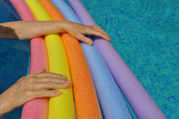 istock Hands on rainbow pool noodles in swimming pool 1543890805