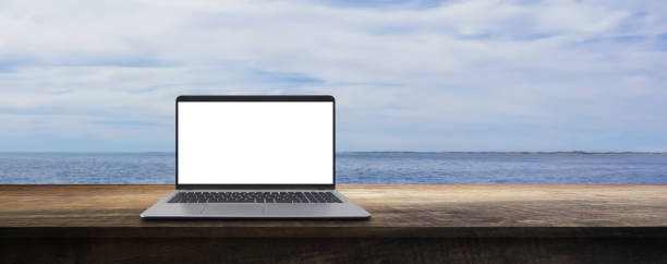 istock empty table with a laptop on the beach on vacation - vacation work concept 1543902822