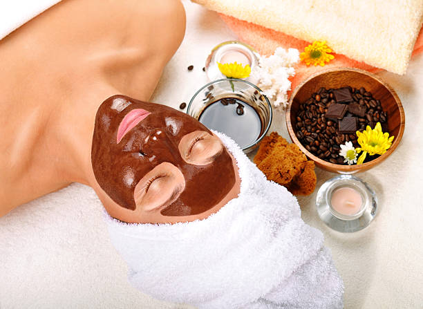Woman in spa atmosphere receiving a chocolate facial beautiful older woman with a chocolate mask on his face, near the coffee. candles, towels and other accessories. sponge bath sponge nature animal stock pictures, royalty-free photos & images
