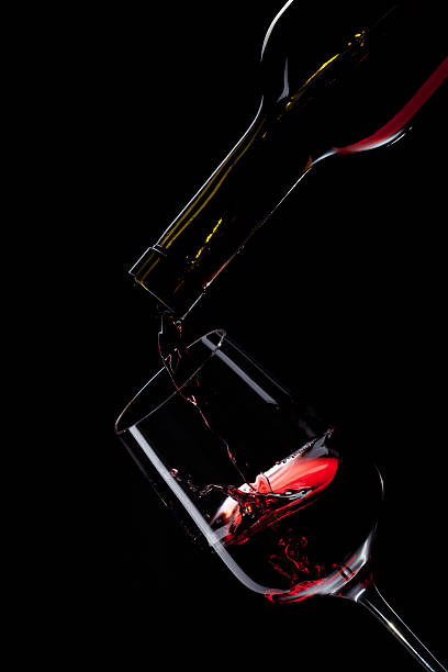 istock red wine pouring into glass isolated on black 154401575