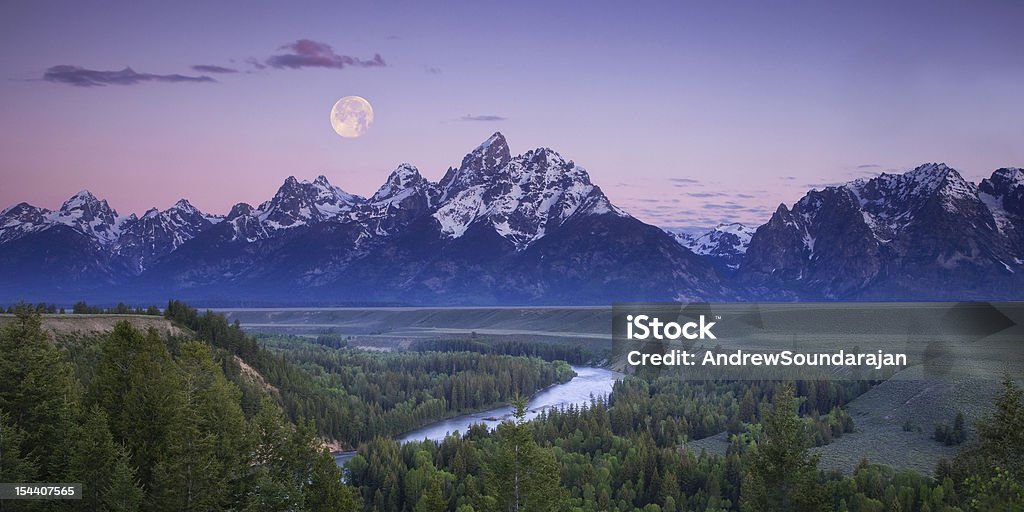 Moon setting over the Tetons Panoramic of a full moon setting over the mountains of Grand Teton National Park prior to sunrise, as seen from the Snake River Overlook.  File sizes up to XL available. Teton Range Stock Photo