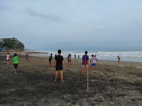 Sukabumi, Indonesia - July 11, 2023: A Group of Teenagers Playing Football on Karang Hawu Beach, West Java, in the Afternoon, Against a Natural Background with a Beautiful Beach Atmosphere.