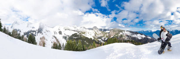 Panorama of two snowboarders looking at cloudy mountains stock photo