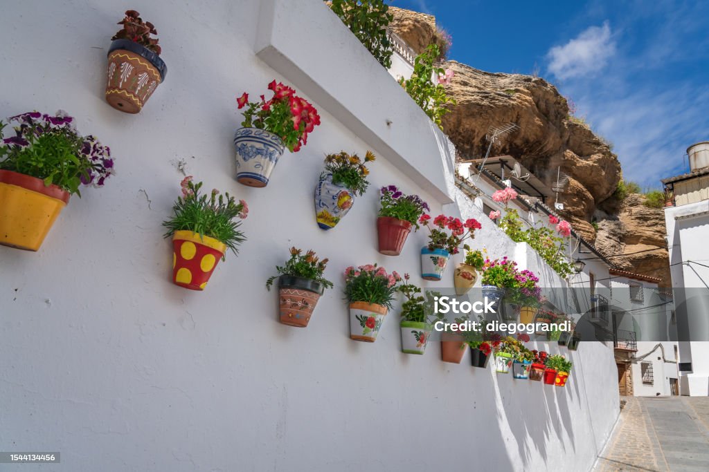 Colorful flower pots and rock overhangs - Setenil de las Bodegas, Andalusia, Spain Setenil Stock Photo