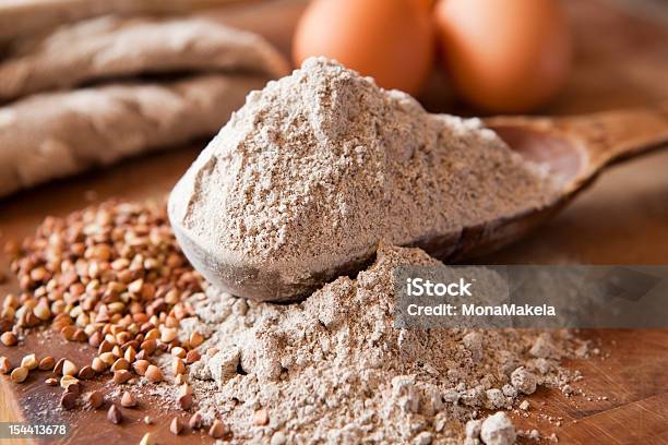Buckwheat Flour Overflowing On Wooden Spoon Stockfoto en meer beelden van Boekweit - Boekweit, Bloem - Stapelvoedsel, Graan