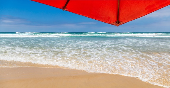 Multicolored beach umbrella against the sun on the background of the beach