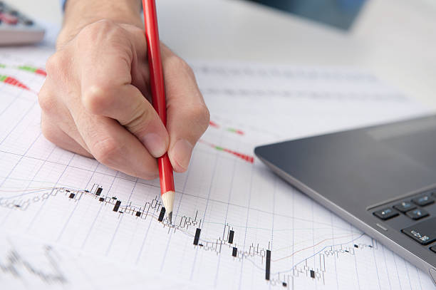 istock male hand pointing at Stock market graphs 154416680