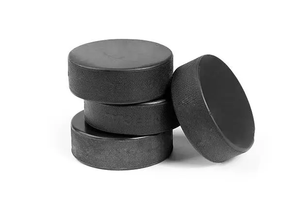 Close-up of a group of four official used black rubber ice hockey pucks isolated on white background.