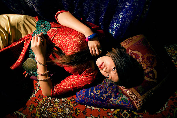 Hippie  girl holding yellow gerbera daisy in nature, lying down on the rug