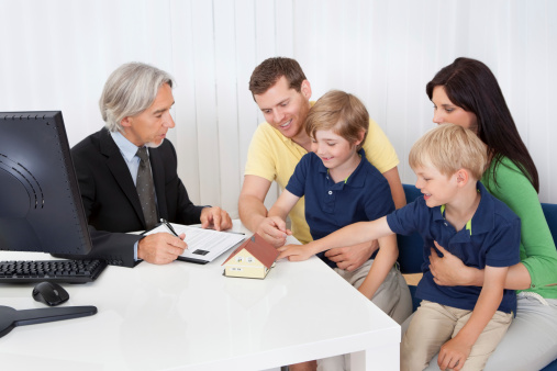 Family in real-estate agency talking construction planner