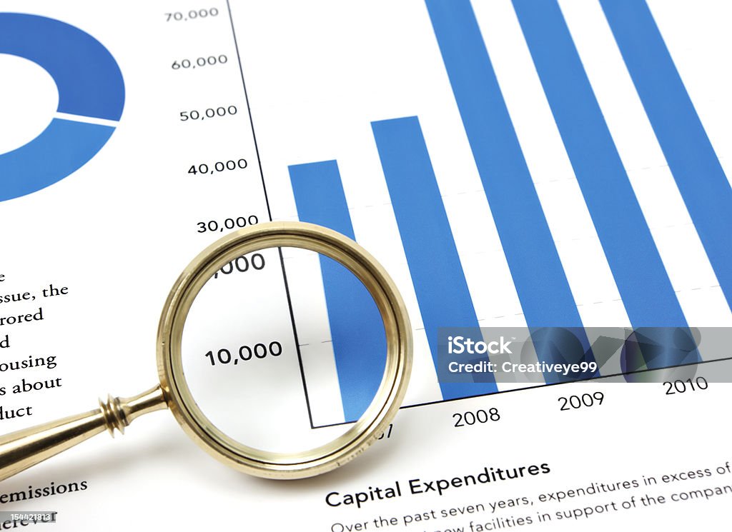 Financial Data Magnifying glass and financial data and graphs. Analyzing Stock Photo