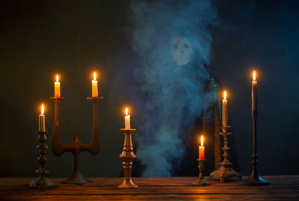 istock Grim reaper with burning candles on wooden table in the dark background 1544253017