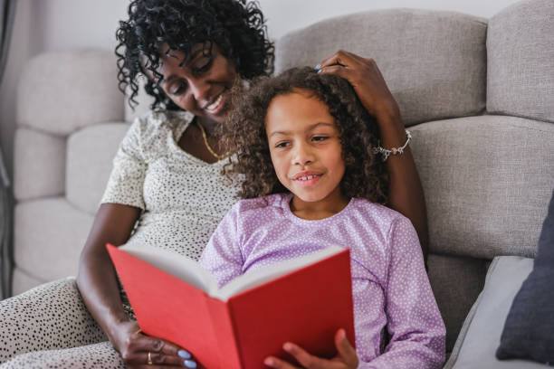 istock Black daughter Learning How to Read While Her Mother Is Lying Next To Her And Supporting Her 1544264514