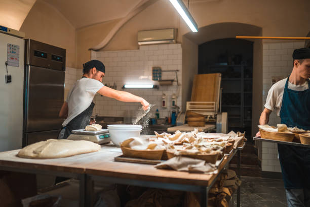 istock Caucasian Baker Sprinkling Flour On A Working Surface In A Bakery 1544266685