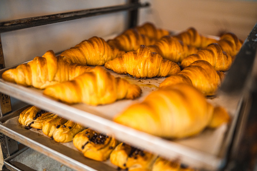 Close up on freshly baked croissants and danishes cooling on a baking tray in an artisan bakery.