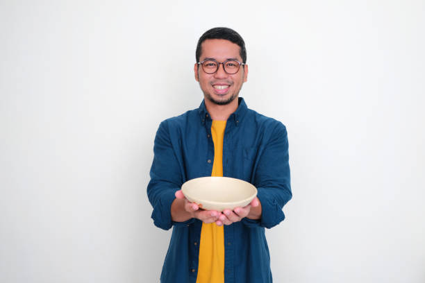 istock Adult Asian man smiling happy while showing empty dinner bowl 1544343646