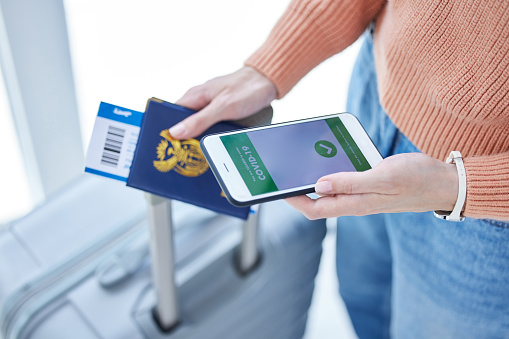 Passport, phone and covid barcode for airport to board airplane for overseas travel, holiday or vacation. Ticket, digital vaccine certificate and closeup of girl with suitcase, document and cellphone