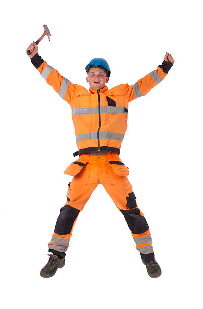Happy builder in working clothes with hammer jumping stock photo