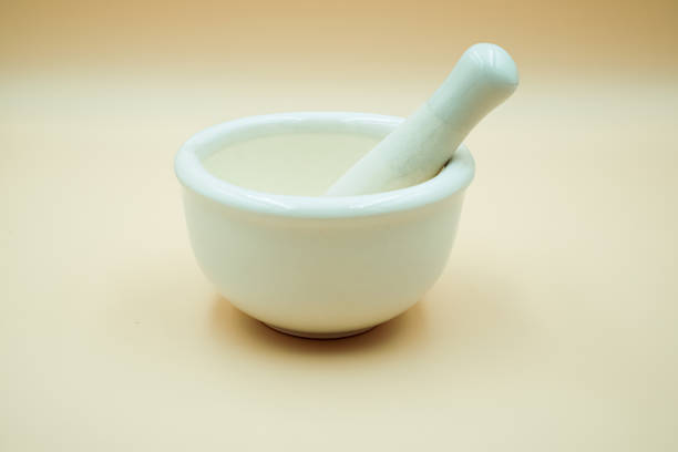 Picture shows a white mortar with a grinder for crushing pills on an orange background.