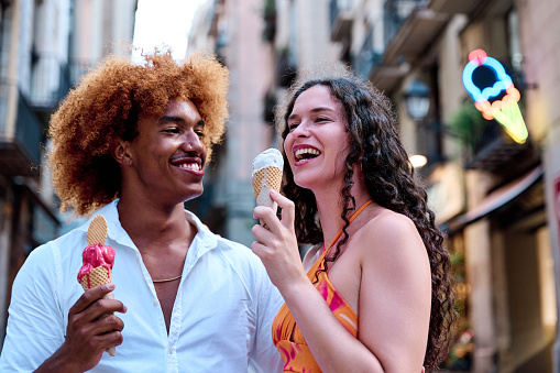 multiethnic couple dating and eating ice cream in summer