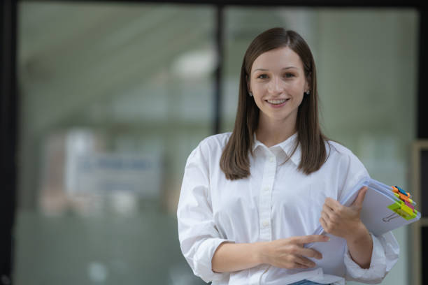 istock Smiling office employee holding a pile of paperwork. 1544718314