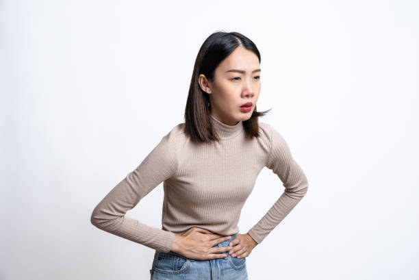 Portrait of beautiful young asian sick woman over isolated white background touching her stomach and feeling bad. Abdominal pain or ache concept. Portrait of beautiful young asian sick woman over isolated white background touching her stomach and feeling bad. Abdominal pain or ache concept. erythema nodosum stock pictures, royalty-free photos & images