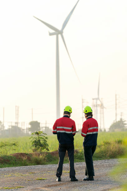 istock Engineers Utilizing Drone Technology to Survey Wind Turbine Farm for Environmental Conservation Engineers discussing and analyzing data while standing amidst a vast wind turbine farm. Utilize a drone to survey the surrounding environment. 1544859560