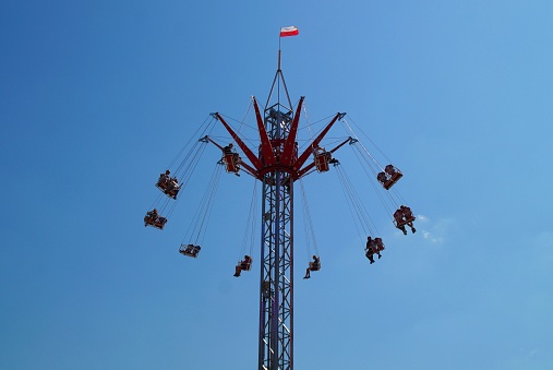 People enjoying the swing ride in amusement park against blue sky