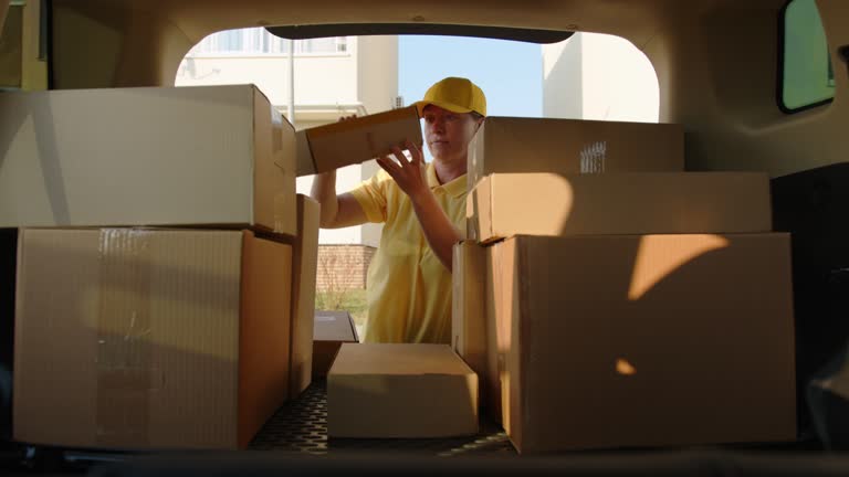 Delivery of goods at home. Deliveryman takes cardboard box in trunk of car to hand over package to customer.