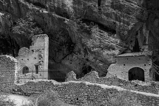 A black and white shot of riders on horses in a desolated rocky area